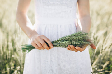 Carefree woman enjoys nature in a wheat field and touches ears of ripe yellow wheat with her hand....