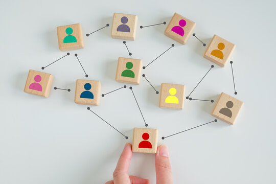 Hand touch red human icon on wooden block from team with line connection symbol for spread influence to people through a communication network. Social connections. Leader and leadership, coordination.