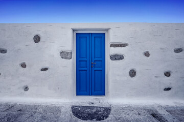 Niebieskie drzwi w białym murze w Grecji