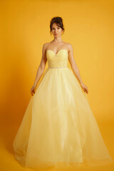 Portrait of a beautiful middle-aged woman in a yellow dress, her hair pulled up against a yellow background