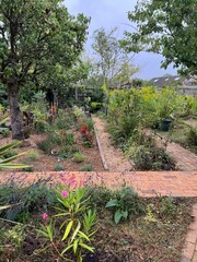 Beautiful landscape of organic garden bed with mediterranean planting of flowers grasses and plants in bed of small smooth pebbles covering soil earth for moisture with design paths espalier pear tree