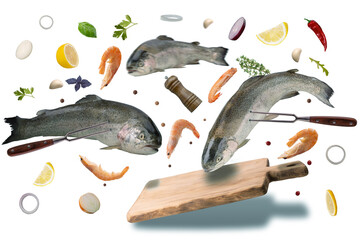 Flying food concept. Rainbow trout fish and shrimp over wooden board with cooking ingredients. Isolated on white background