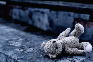 Dirty teddy bear toy lies outdoors on the road as symbol of children's loneliness, pain, loss...