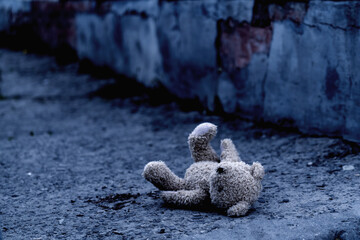 Dirty teddy bear toy lies outdoors on the road as symbol of children's loneliness, pain, loss...