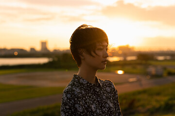 夕日 河川敷 ショートヘアの女性