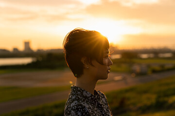 夕日 河川敷 ショートヘアの女性