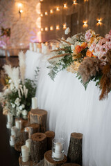 Romantic boho main table. Wedding decor with dried flowers floristry, stumps, and candles, boho style. Pampas grass