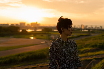 夕日 河川敷 ショートヘアの女性