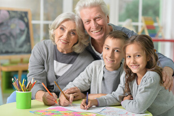 Fototapeta premium Portrait of grandparents and grandchildren drawing at home