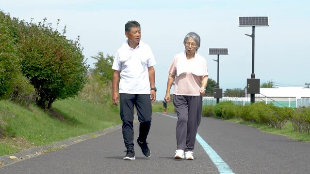 公園でウォーキング・有酸素運動する高齢者の男女
