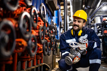 Heating plant worker changing industrial pipe valves as regular maintenance process.