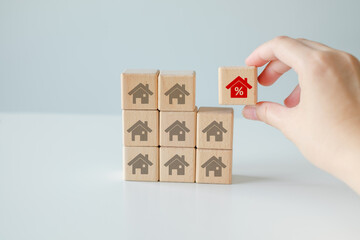 Real estate, Property investment and asset management concept. Interest rates, loan mortgage, house tax, discount and sale price. Hand choosing house with percentage sign from many houses.
