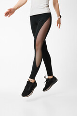 slim female legs in black sport leggings jumping