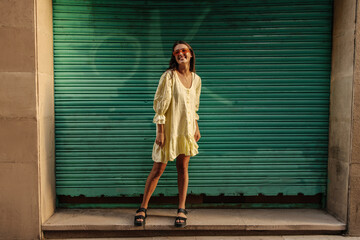 Full length pretty young caucasian woman relaxing walking outdoors during day. Brunette wears summer spacious sundress. Concept of enjoying moment