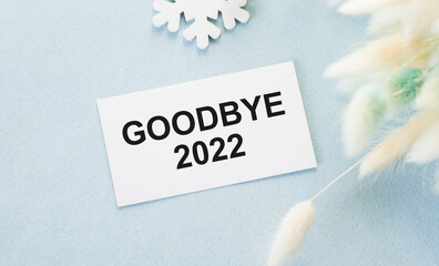 Goodbye 2022 text on a card on a blue background, business concept
