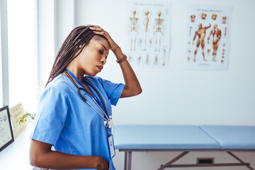 Shot of a young female nurse looking stressed out while standing at a window in a hospital. Tired...
