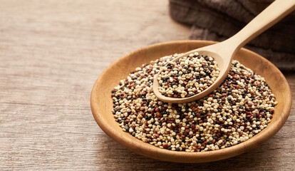 quinoa seeds in wooden spoon and plate on wood table background. quinoa seeds                                                      