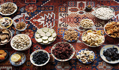 Eastern feast. Asian still life of dried fruits and nuts in plates on a carpet