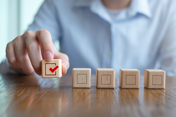 Elections and Voting, Vote, to do list, checklist, Task list, Survey and assessment concept. Hand holding check mark on wooden block and blank check box on wooden cubes.