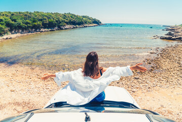 woman laying at car hood with view of sea summer beach