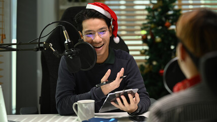 Young podcaster using a microphone and laptop computer recording audio for channel in home studio