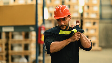 Warehouse workers in safety uniform working in warehouse full of tall shelves with goods in cardboard boxes