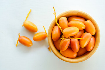 Fresh dates in wooden bowl on white background, top view.