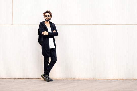 beautiful young man with sunglasses leaning in a white wall, concept of urban lifestyle and stylish clothing, copy space for text