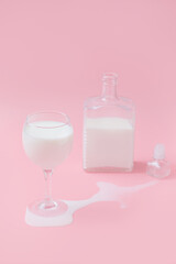 glass with milk and a graph in the background. pink background. puddle of spilled milk.