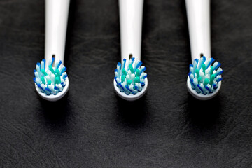 some 3 electric toothbrush heads isolated on black dark structured paper. daily routine hygiene use...