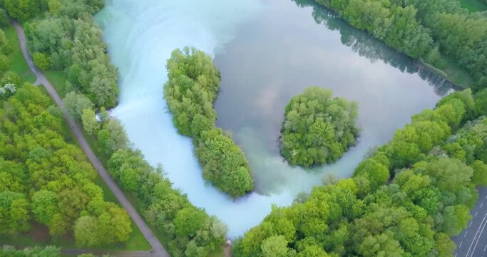 Lush forest, clouds reflected on blue water lake, Bochum Werne, Germany