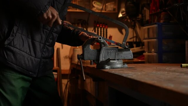 Man Using a hacksaw, cutting a pipe.