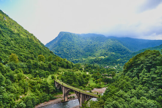 Mountain landscape with an abandoned stone bridge over the river.