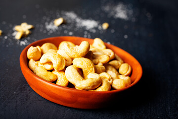 cashew nuts in bowl on dark table, top view