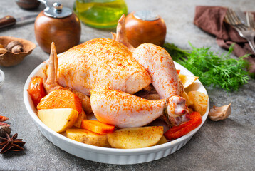 Raw chicken marinated in sour cream sauce with vegetables is in a white tray.