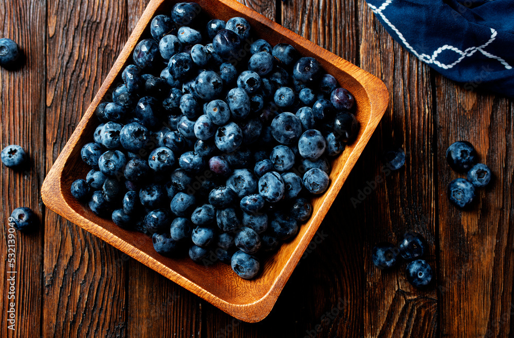 Canvas Prints freshly picked blueberries in wooden bowl. juicy and fresh blueberries with green leaves on rustic t