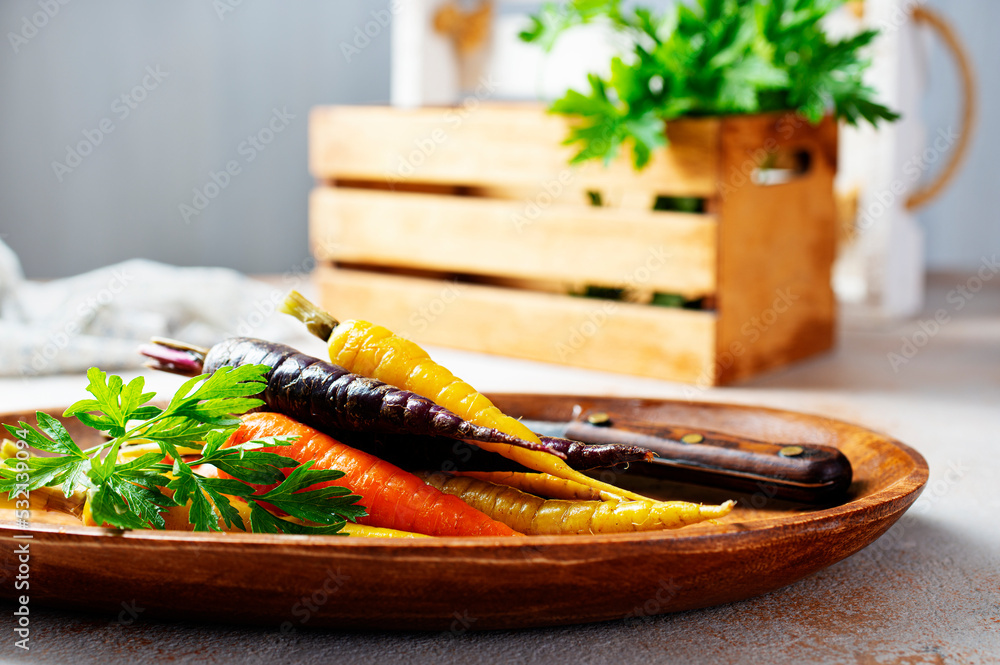 Wall mural carrots of different varieties with green tops. a bunch of carrots of different colors on a gray bac