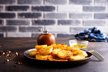Fried potato wedges with oil, herbs on stone board