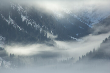 Austrian mountains covered with snow and surrounded by clouds