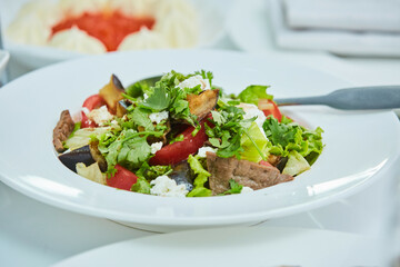 Meat and vegetable salad on a plate. Beautiful serving of food in a restaurant.