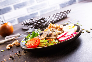 Cooked Buckwheat with avocado and mushrooms served in a bawl for breakfast. Gluten free meal.