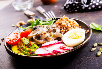 Cooked Buckwheat with avocado and mushrooms served in a bawl for breakfast. Gluten free meal.