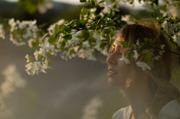 closeup sideview portrait of looking away attractive caucasian woman among the flowering apple tree