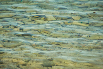Big pebble stones below clear blue water