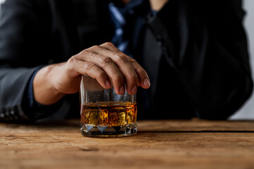 Sad depressed addicted drunk guy, Alone asian man drinker alcoholic sitting at bar counter with glass drinking whiskey.