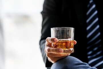 Sad depressed addicted drunk guy, Alone asian man drinker alcoholic sitting at bar counter with glass drinking whiskey.