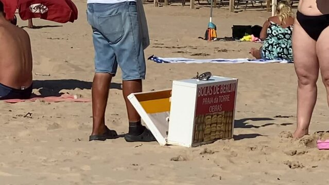 close up of the Berlin Balls (bolas de Berlim) man delivering on beach. Portuguese fried dough with sugar, Filled with sweet cream. Cascais (Praia da Torre)