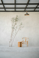 a wooden chair and table with tree in front of cement wall