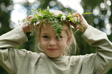 Pagan ritual, close-up portrait of a child girl with a wreath in the forest.