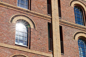 Sun Star, old house facade made of red bricks with semicircular mullioned windows and a sun star in the window pane.